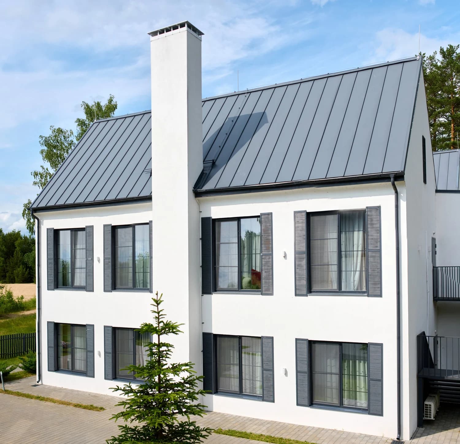 modern white house with metal roof in suburban setting